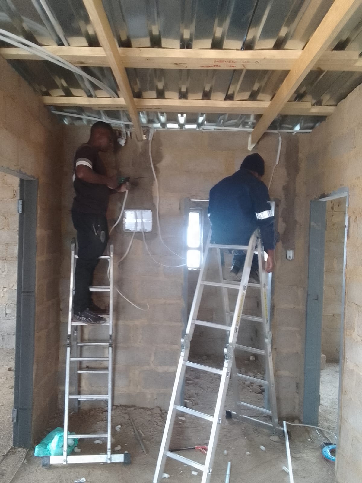Technician running wiring inside a ceiling space